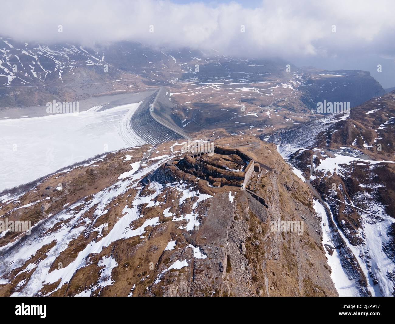 Vista aerea di antiche rovine fortilizio in montagna vicino al lago ghiacciato e diga Foto Stock