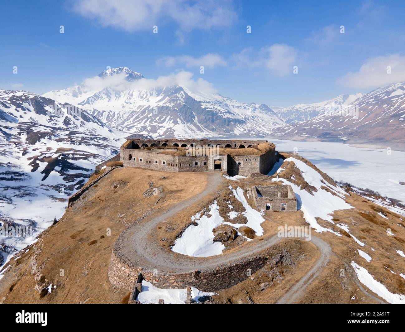 Vista aerea di antiche rovine fortilizio in montagna vicino al lago ghiacciato e diga Foto Stock