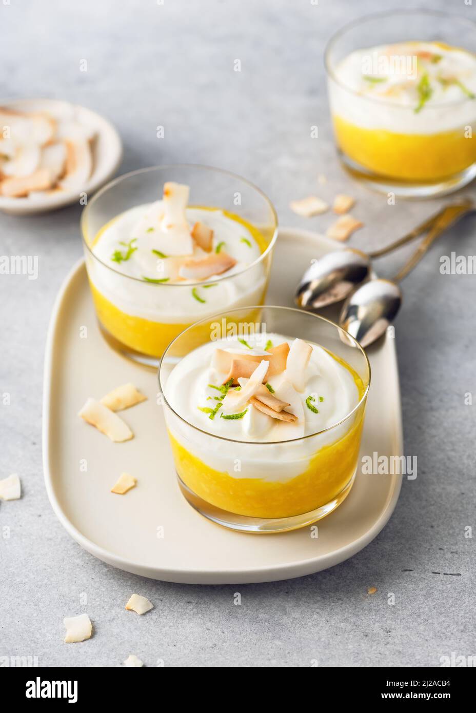 Dessert alla crema di frutta tropicale con strati bianchi e arancioni di purea di mango e formaggio cremoso. Cibo vegano. Foto Stock