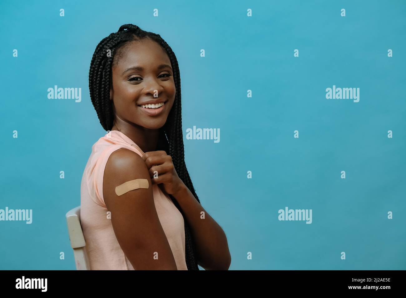 Vaccinato attraente giovane donna sorridente con intonaco a portata di mano subito dopo aver ottenuto il vaccino covid-19 sparato Foto Stock