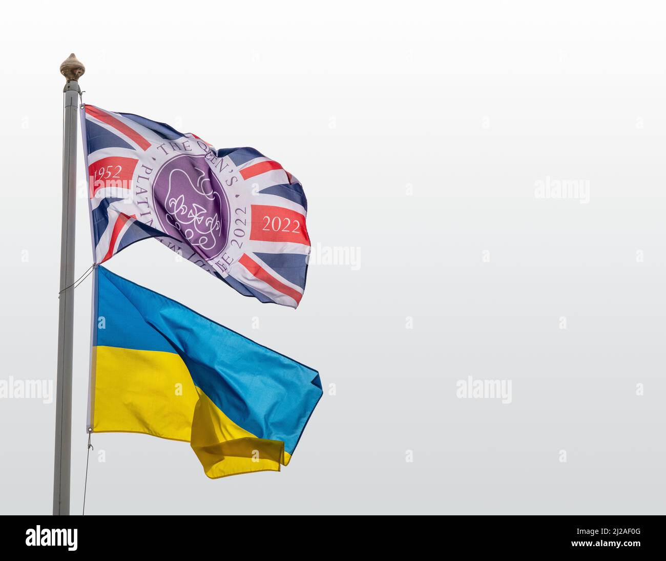 La bandiera Platinum Jubilee Union Jack vola su un palo insieme alla bandiera bicolore della Repubblica popolare Ucraina con cielo chiaro chiaro chiaro alle spalle Foto Stock