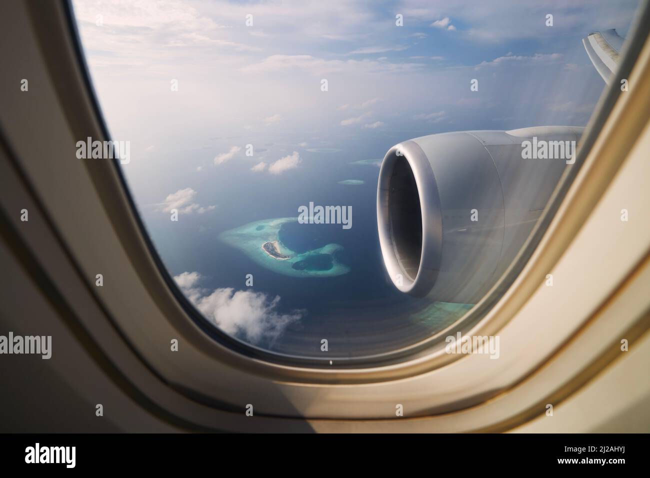 Vista dalla finestra dell'aeroplano durante l'atterraggio alle Maldive. Oceano Indiano con bellissime isole tropicali in un idilliaco giorno di sole. Foto Stock