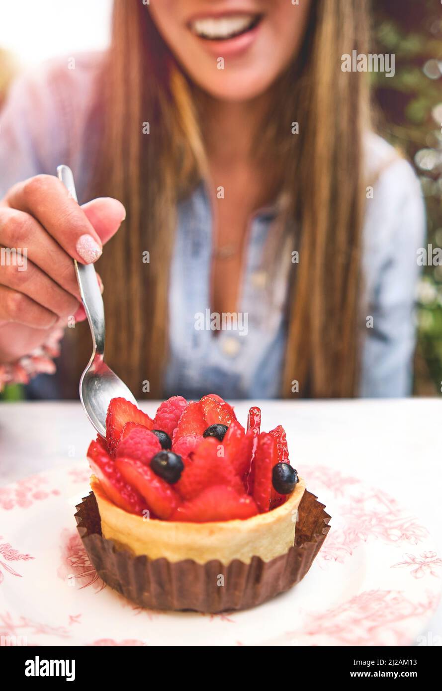 Giovane donna che degusta torta con fragole, fuoco selettivo. Foto Stock