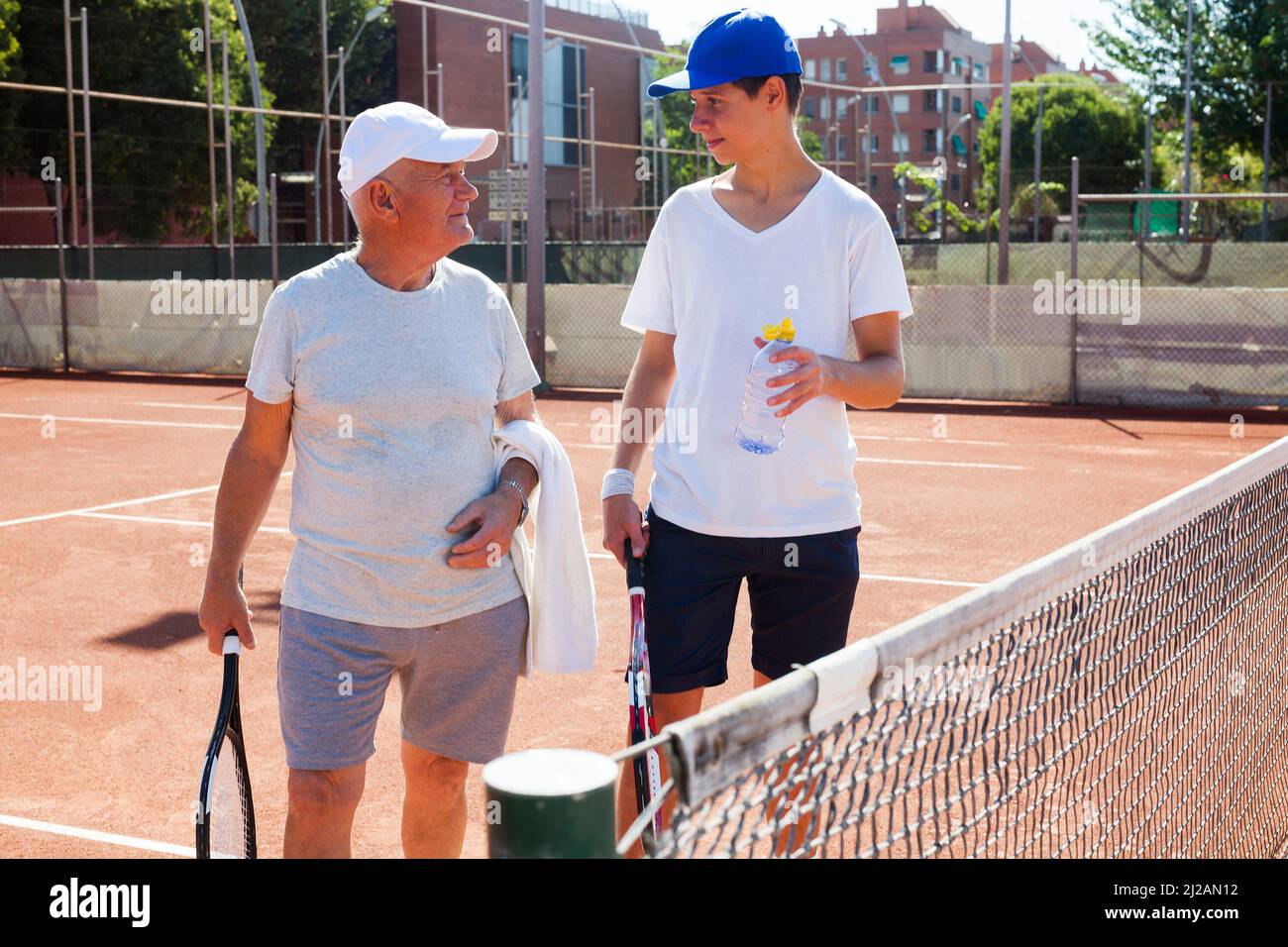 nonno e nipote parlano sul campo giocando a tennis Foto Stock