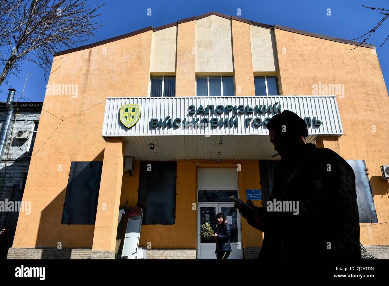 ZAPORIZHZHIA, UCRAINA - 29 MARZO 2022 - Un uomo che fuma una sigaretta tiene un telefono cellulare in attesa fuori dell'ospedale militare di Zaporizhzhia, Zaporizhzh Foto Stock
