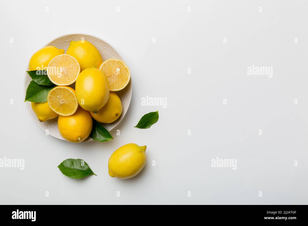 Limone tagliato fresco e limoni interi su piatto rotondo su sfondo colorato. Cibo e bevande ingredienti preparazione. Tema di cibo sano vista dall'alto Vith c Foto Stock