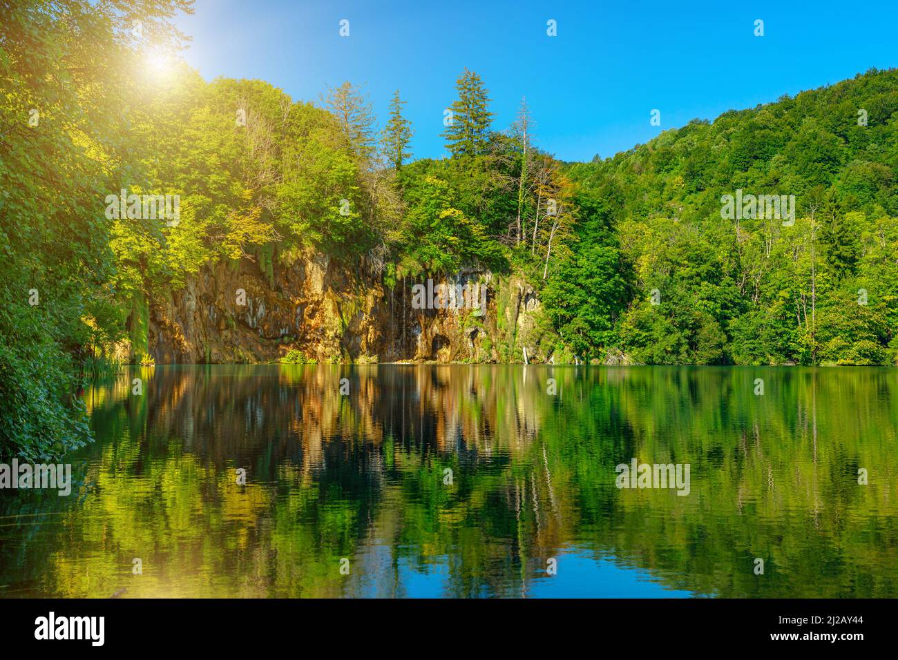 Sole sul lago Galovac con piccola cascata nel Parco Nazionale dei Laghi di Plitvice in Croazia nella regione di Lika. Sito patrimonio dell'umanità dell'UNESCO. Foto Stock