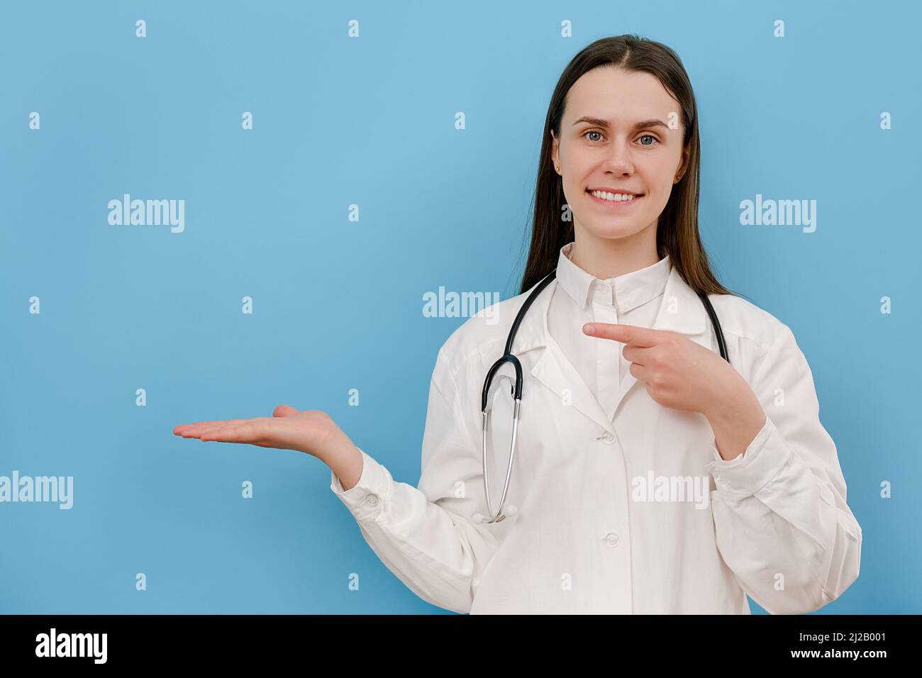 Ritratto di giovane donna felice in professionale medico bianco cappotto indica con mani su spazio copia per la pubblicità. Dottore che presenta e mostra s Foto Stock