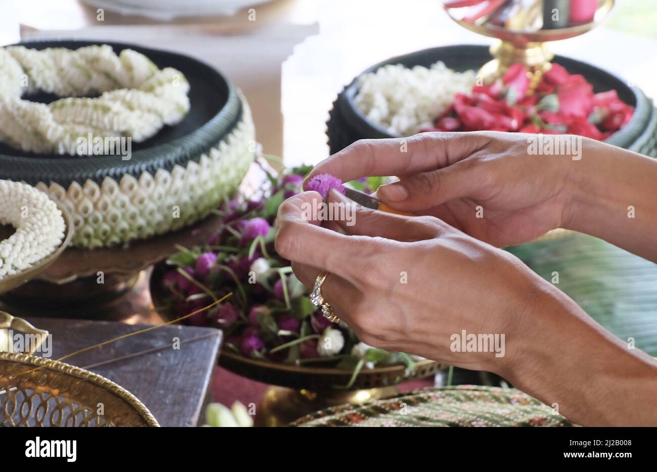 Donna a mano che fa belle ghirlande o ghirlande con Amaranth Flower, la ghirlande in stile tradizionale tailandese. Foto Stock