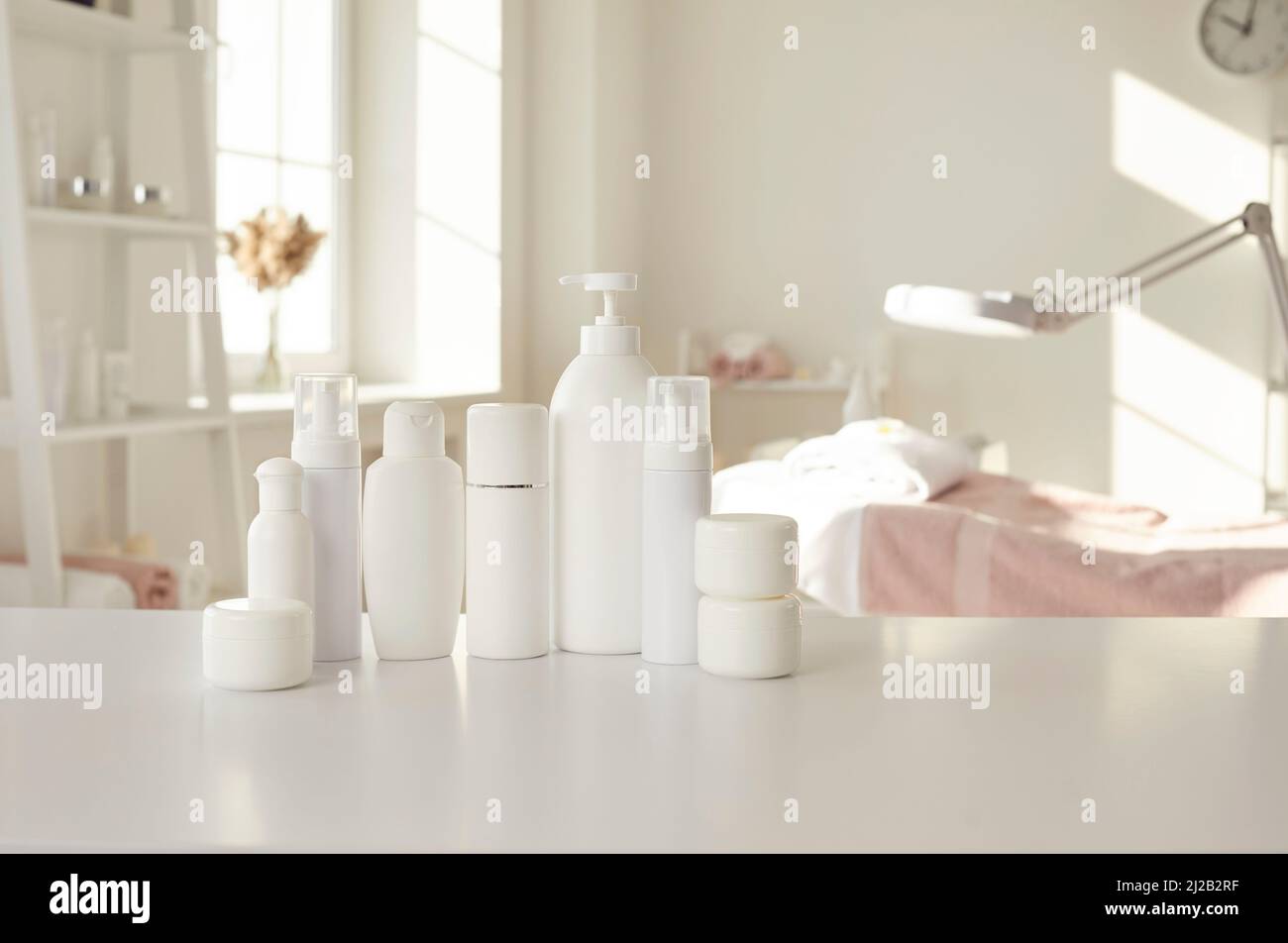 Bottiglie e vasetti in mockup con prodotti per la cura della pelle sul tavolo in spa e salone di bellezza Foto Stock