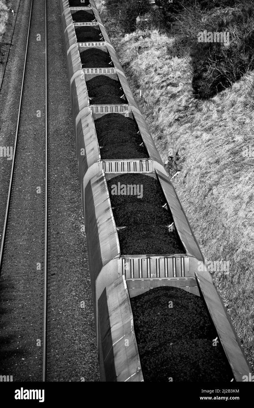 Carico pioggia di carbone polverizzato importato utilizzato per la produzione di elettricità trasportato in DB Schenker HTA merry go vagoni rotondi Foto Stock