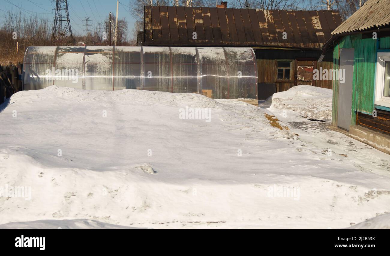 Giardino d'inverno con una serra coperta da uno spesso strato di neve Foto Stock