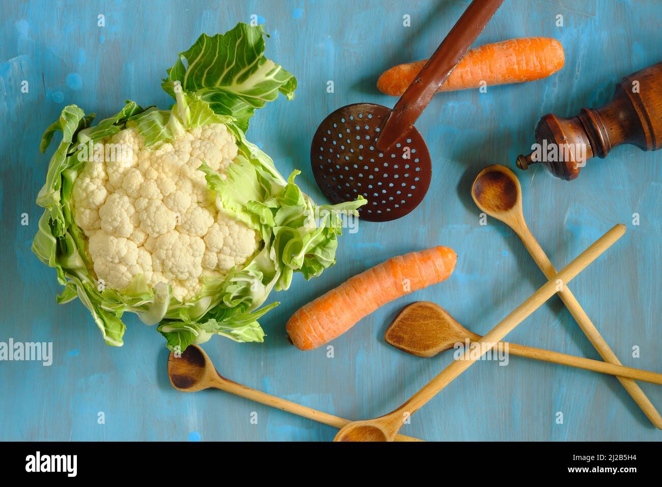 Piatto con cavolfiore fresco, cucchiai di legno e carote.sano mangiare, dieta, concetto di cibo vegano. Foto Stock