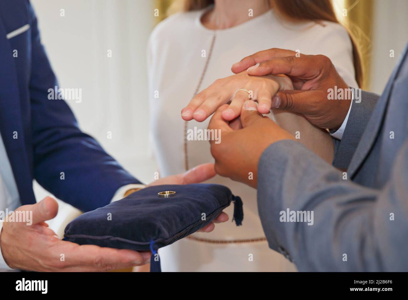 Coppia mista di corsa che tiene le mani e scambiando gli anelli di nozze Foto Stock
