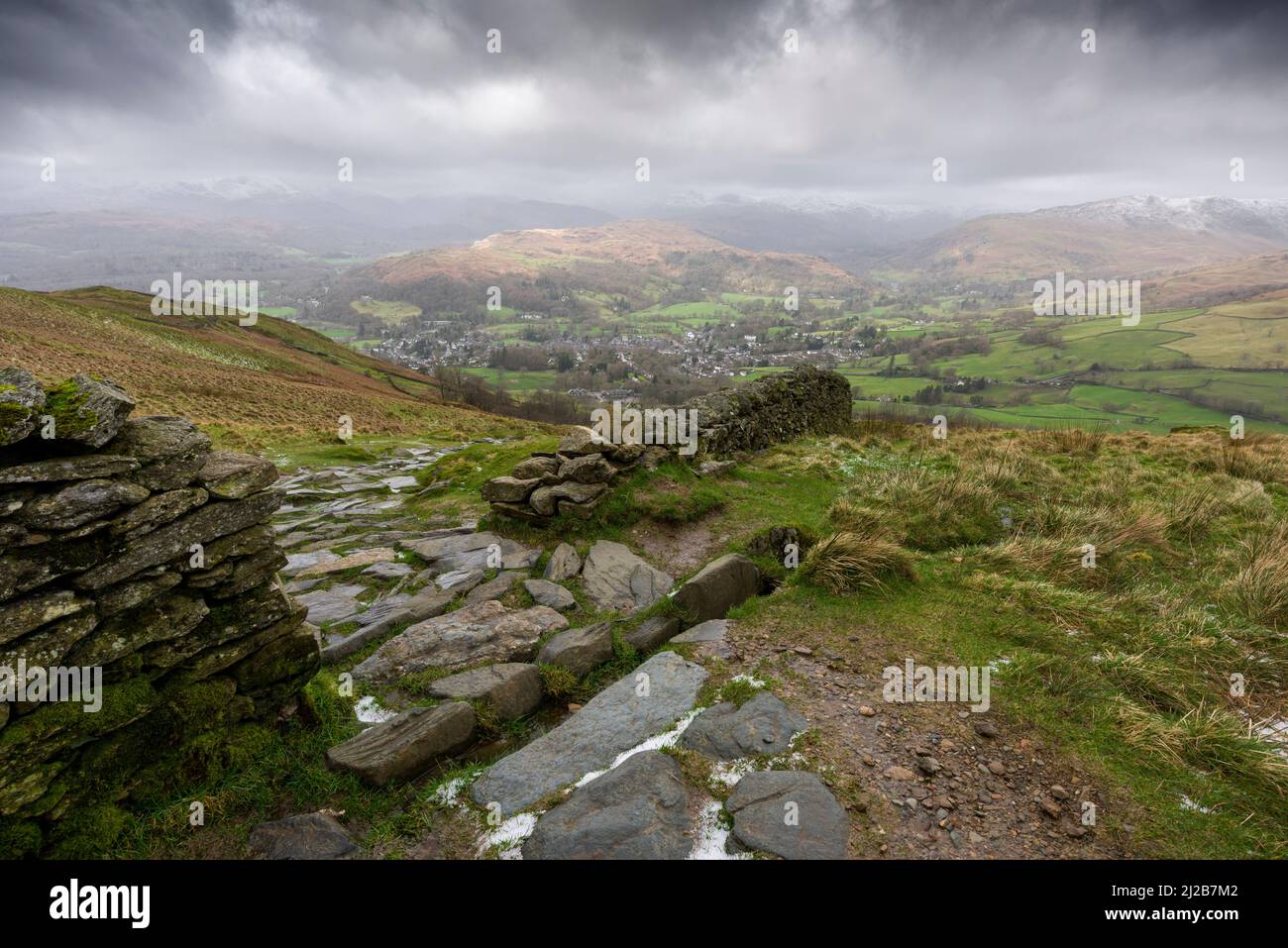 La vista ad ovest da Wansfell sopra Ambleside, Loughrigg cadde e le montagne innevate della Cumbria oltre nel Parco Nazionale del Distretto del Lago, Cumbria, Inghilterra. Foto Stock