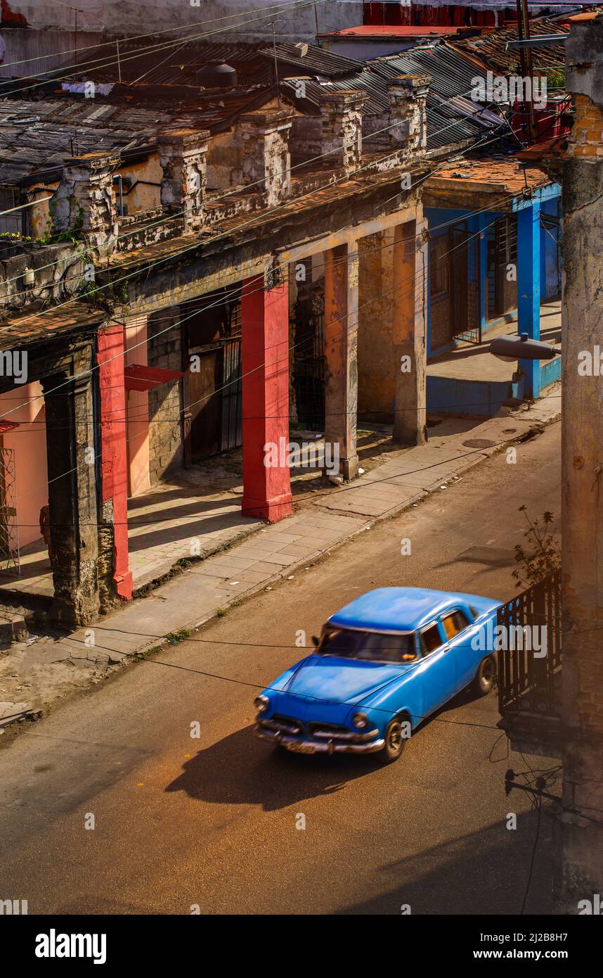 American made vecchia auto blu su una strada deserta a Cuba circondata da un'architettura dilapidata Foto Stock