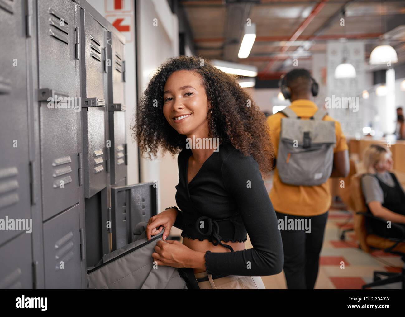 Una giovane donna multietnica si prepara per la giornata universitaria presso gli armadietti del campus Foto Stock