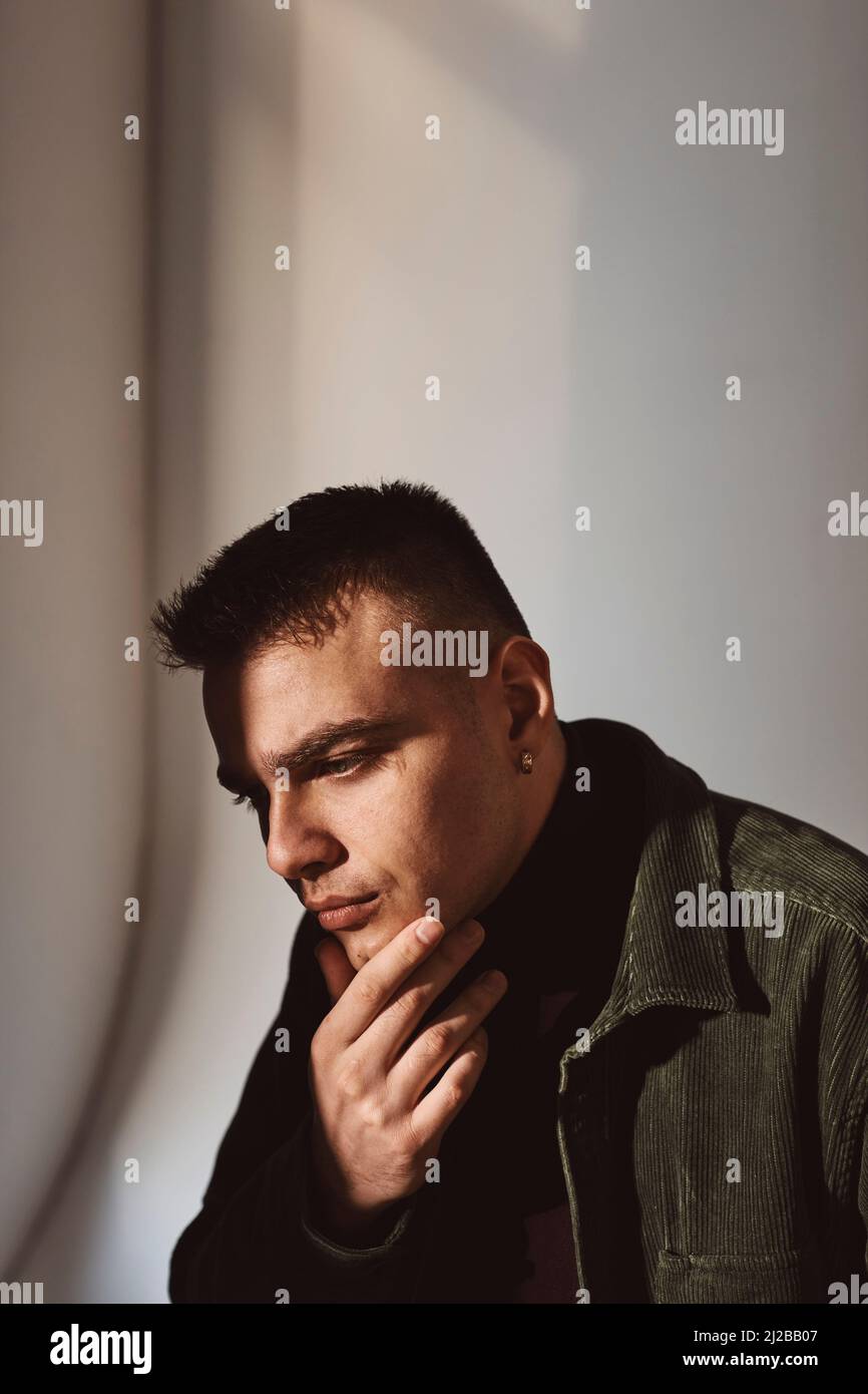Uomo contemplativo con mano sul mento contro il muro Foto Stock