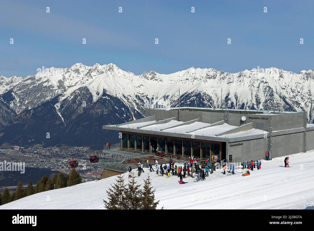 Gli sciatori si radunano fuori dal ristorante Das Kofel presso la stazione di montagna del Patscherkofelbahn, mentre la gondola sorge sopra la valle dell'Inn e Innsbruck. Foto Stock