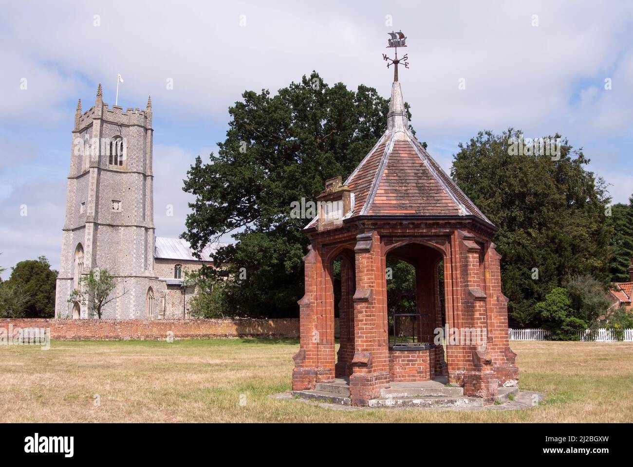 Veduta della chiesa di San Pietro e di San Paolo e la coperta pompa del villaggio, Heydon Village, Norfolk, Inghilterra Foto Stock