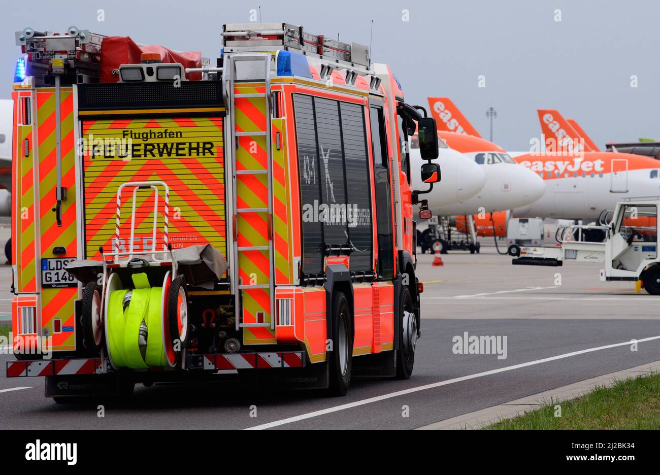 31 marzo 2022, Berlino, Schönefeld: Durante un evento stampa per l'inizio della formazione presso il reparto antincendio dell'aeroporto, un veicolo ausiliario del gruppo antincendio (HLF) guida gli aerei in attesa attraverso i terreni dell'aeroporto a scopo dimostrativo. Il veicolo differisce da un normale camion dei pompieri per il fatto che dispone di attrezzature più estese per l'assistenza tecnica. A partire da agosto 2022, il reparto antincendio del sito di BER offrirà formazione per diventare un pompiere. All'inizio devono essere occupate sei posizioni apprendisti. Foto: Soeren Stache/dpa-Zentralbild/dpa Foto Stock