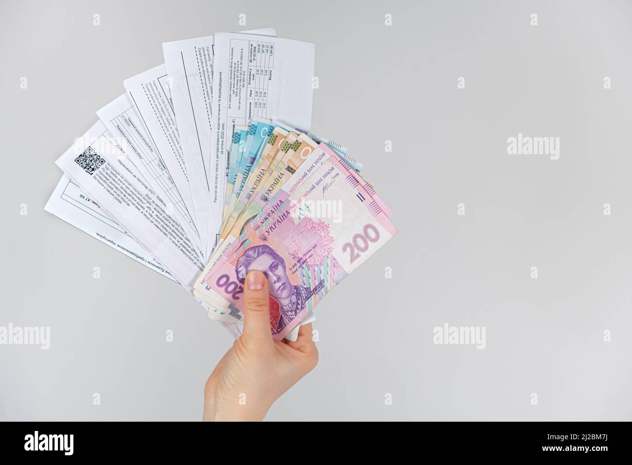 Le banconote di hryvnia e i pagamenti per i servizi pubblici sono nelle mani di una persona. 21 marzo 2022, Zaporozhye, Ucraina. Foto Stock