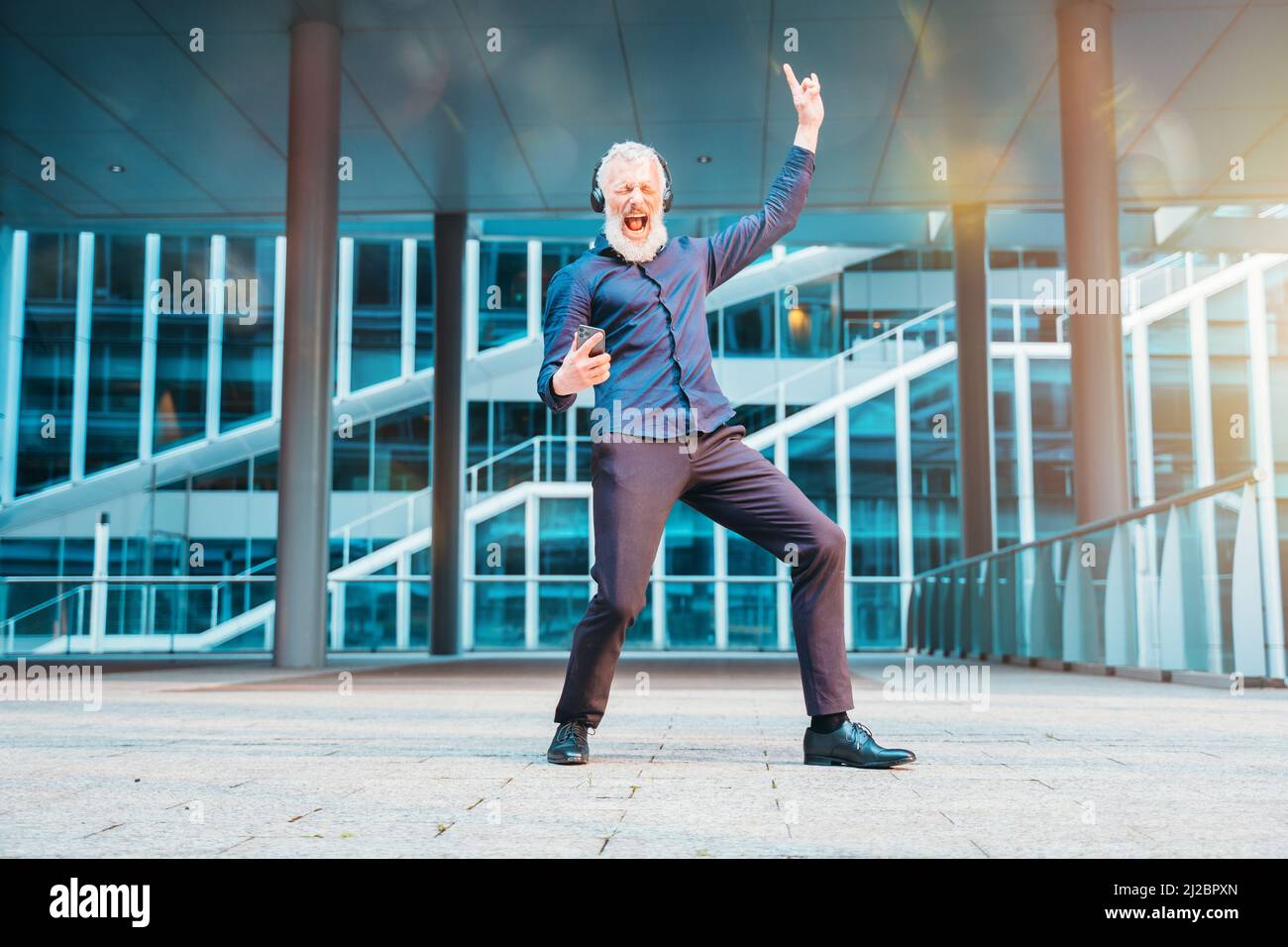 Energico uomo d'affari balla e ascolta musica Foto Stock