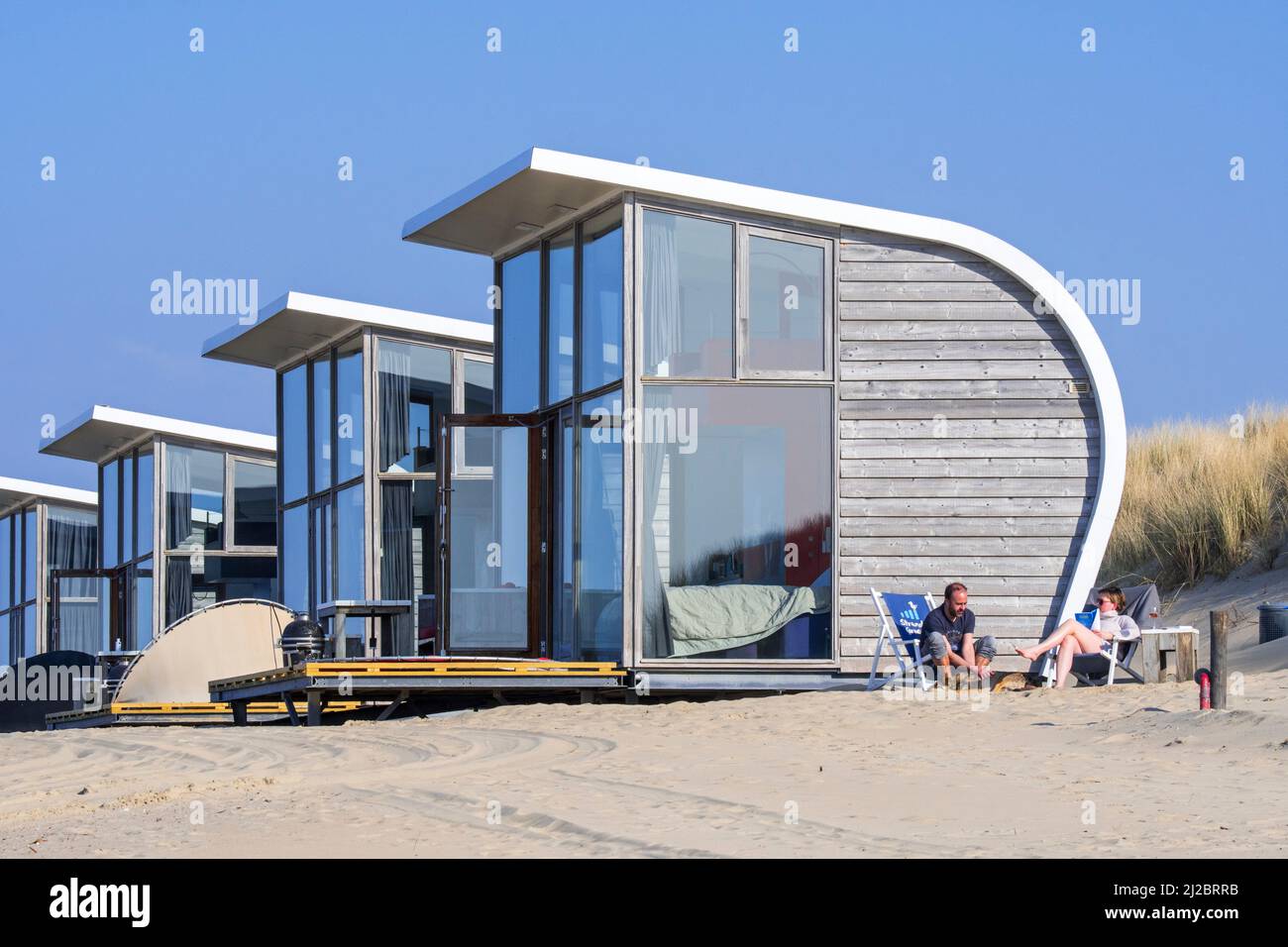 Fila di case piccole / case da spiaggia in affitto sulla spiaggia di sabbia lungo la costa del Mare del Nord a Groede, Zeeland, Paesi Bassi Foto Stock