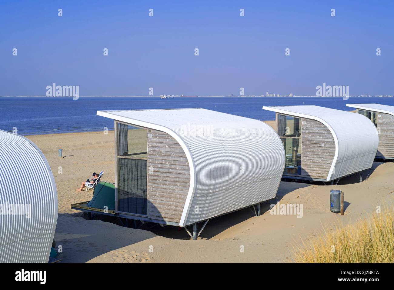 Fila di case piccole / case da spiaggia in affitto sulla spiaggia di sabbia lungo la costa del Mare del Nord a Groede, Zeeland, Paesi Bassi Foto Stock