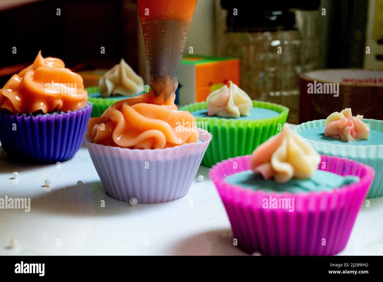 macro shot di ghiaccio piping su cupcakes di colore bianco e blu per fare bei disegni su prodotti da forno e saponi come un business a casa per gli ospiti Foto Stock