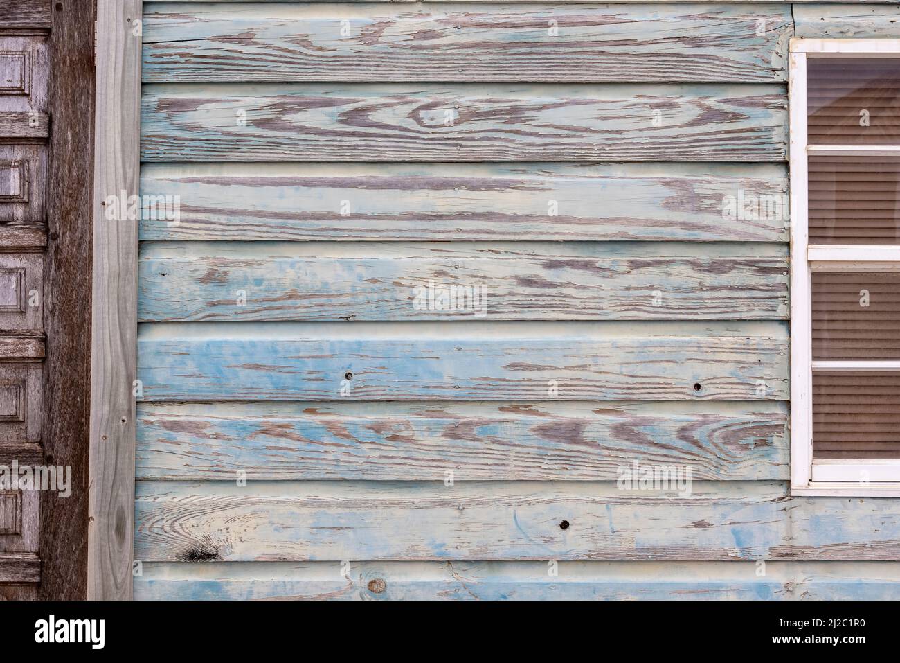 sfondo: facciata in legno di colore bluastro, brunastro e verdognolo, porta e finestra marroni con framing bianco Foto Stock