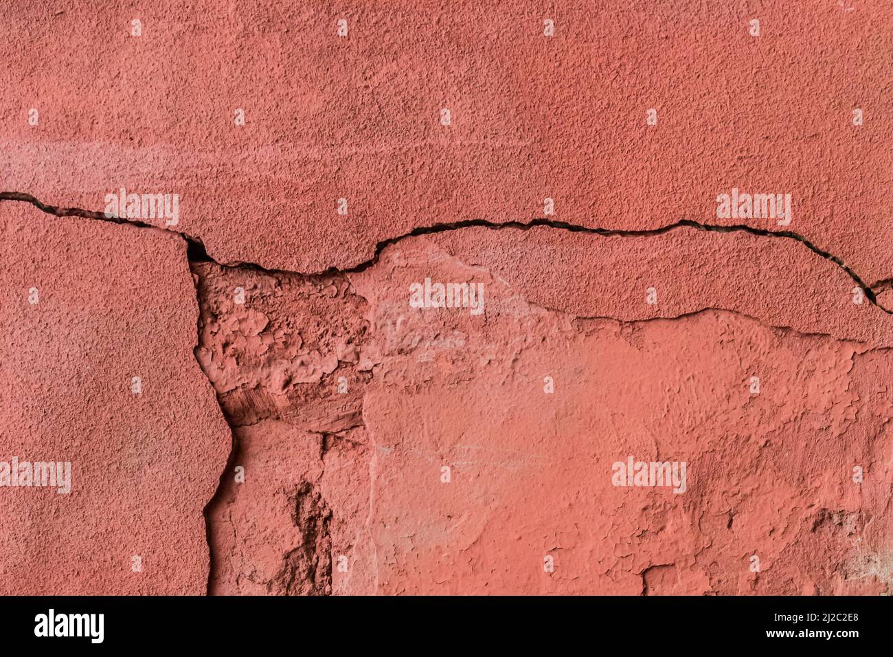 Vecchia crepa rotto muro di cemento rosso danno sfondo cemento fessurato struttura. Foto Stock