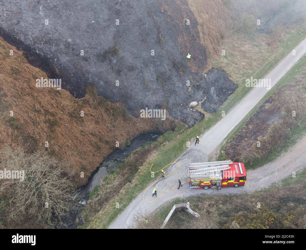 Cork, Irlanda, 31st marzo 2022. Cork City Fire Brigade Deals with a large Gorse Fire Near Houses in the Glen Park, Cork, Ireland. Foto aerea dei membri della Brigata del fuoco di Cork City che si occupa di un altro grande fuoco di gorse che brucia vicino alle case nel Glen River Park che corre tra il Glen e Ballyvolane. Poco dopo le 6 di questa sera i Vigili del fuoco di Cork City hanno assistito alla scena di un grande fuoco di gorse che brucia vicino alle case in Glen River Park, il fumo da questo fuoco è saltato direttamente nelle case nella zona di Glen sopra Glen Park. Un certo numero di vigili del fuoco potrebbe essere visto assistere a. Foto Stock