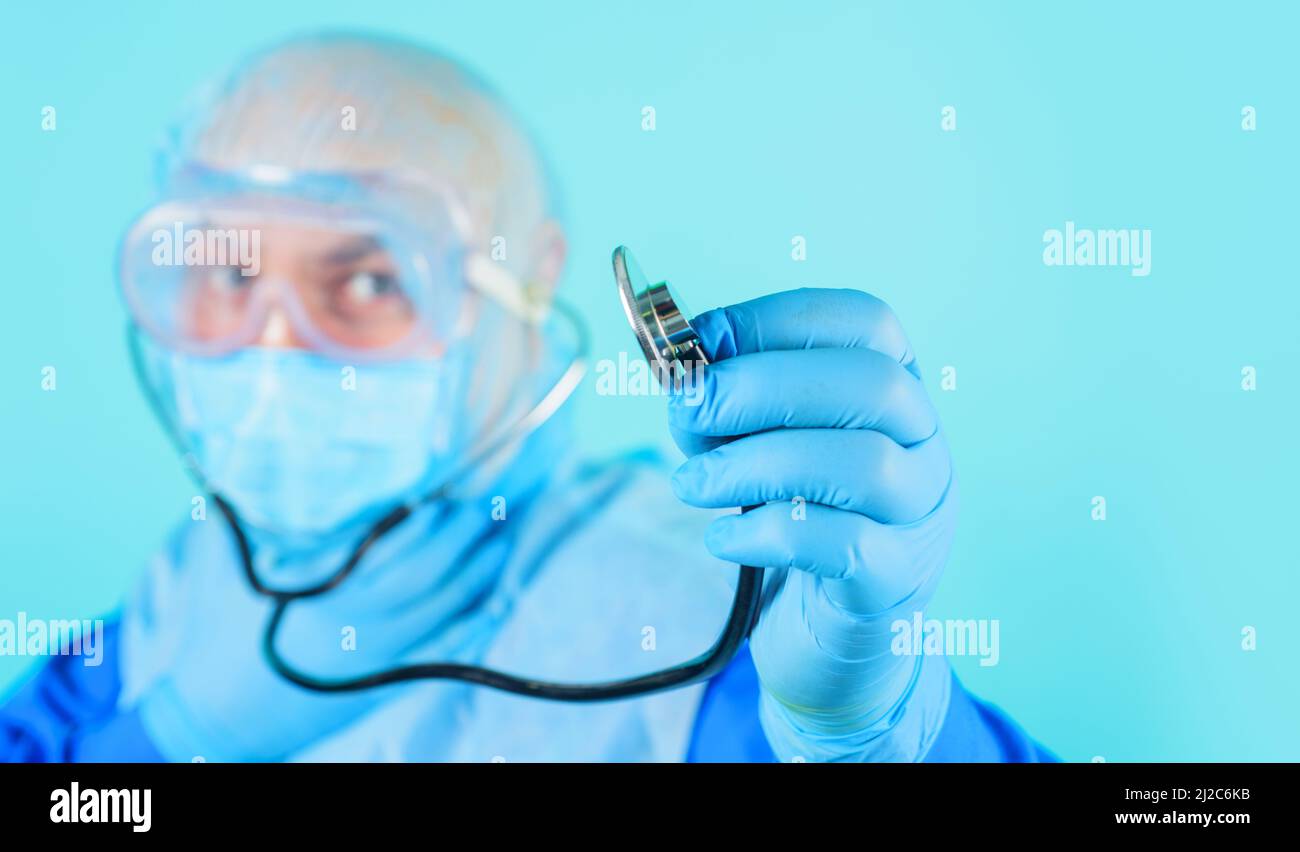 Medico in tuta protettiva e maschera medica con stetoscopio. Pubblicità ospedale, clinica. Foto Stock