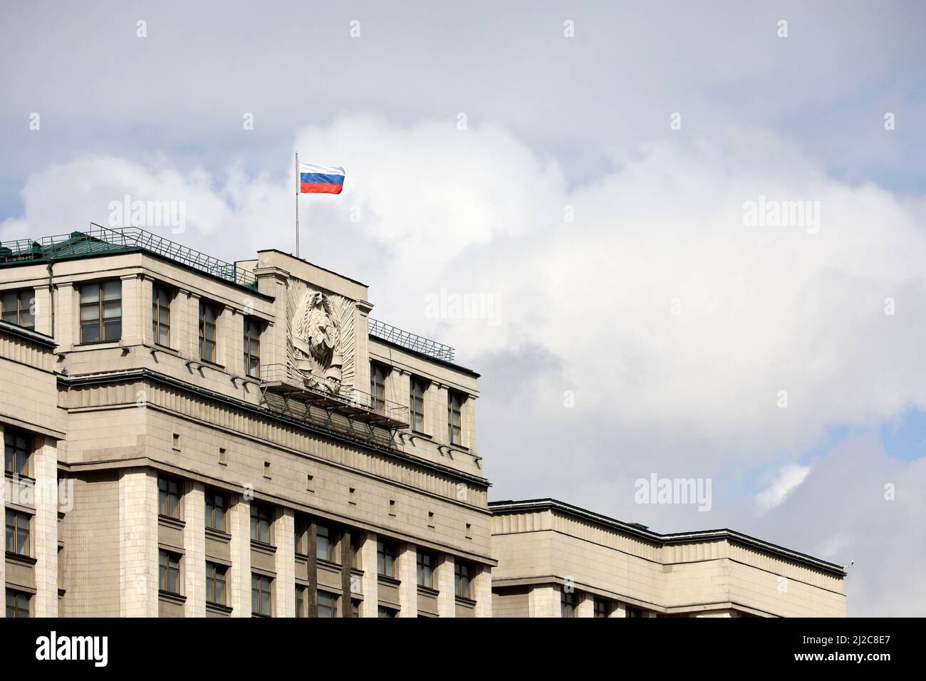 Bandiera russa sul palazzo del parlamento a Mosca sullo sfondo del cielo blu e delle nuvole bianche, autorità della Russia Foto Stock