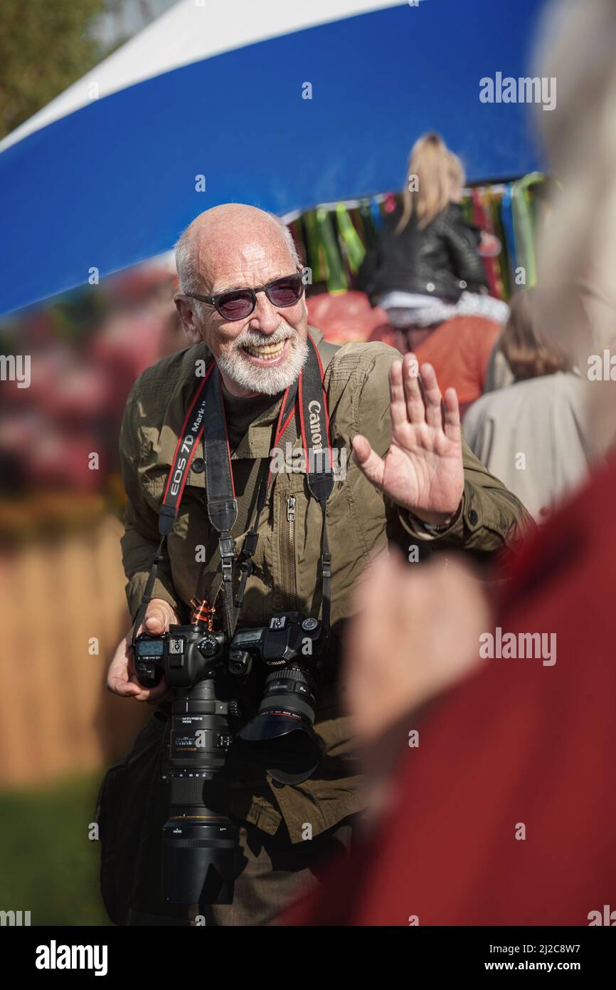 Mosca, Russia , 1 ottobre 2016,. Cossack Gathering. Un fotografo anziano dai capelli grigi sorride allegro con una macchina fotografica in mano. Un allegro Foto Stock