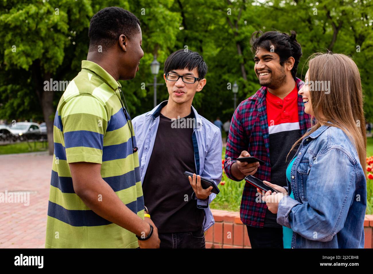 Un gruppo di studenti diversi comunica facilmente dopo le lezioni universitarie. Stabilire forti legami tra giovani di razze e nazionalità diverse Foto Stock