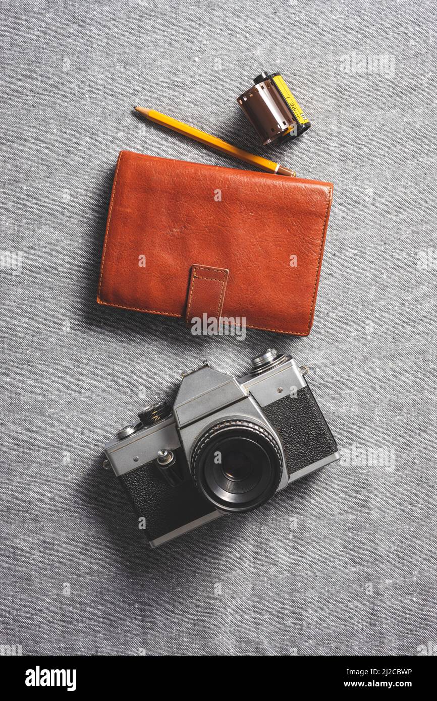 Telecamera analogica retrò. Fotocamera vintage vecchio stile con obiettivo con notebook e rotolo di pellicola fotografica su panno. Vista dall'alto. Foto Stock