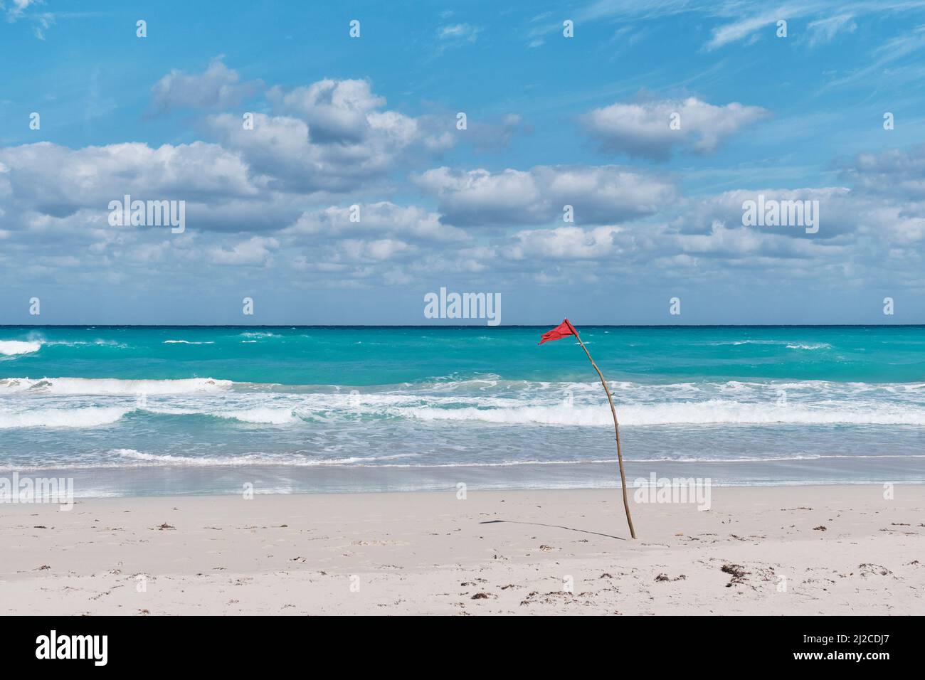 Bandiera rossa sulla spiaggia sabbiosa dell'Oceano Atlantico, Varadero, Cuba. Cartello di pericolo, è vietato nuotare. Foto Stock