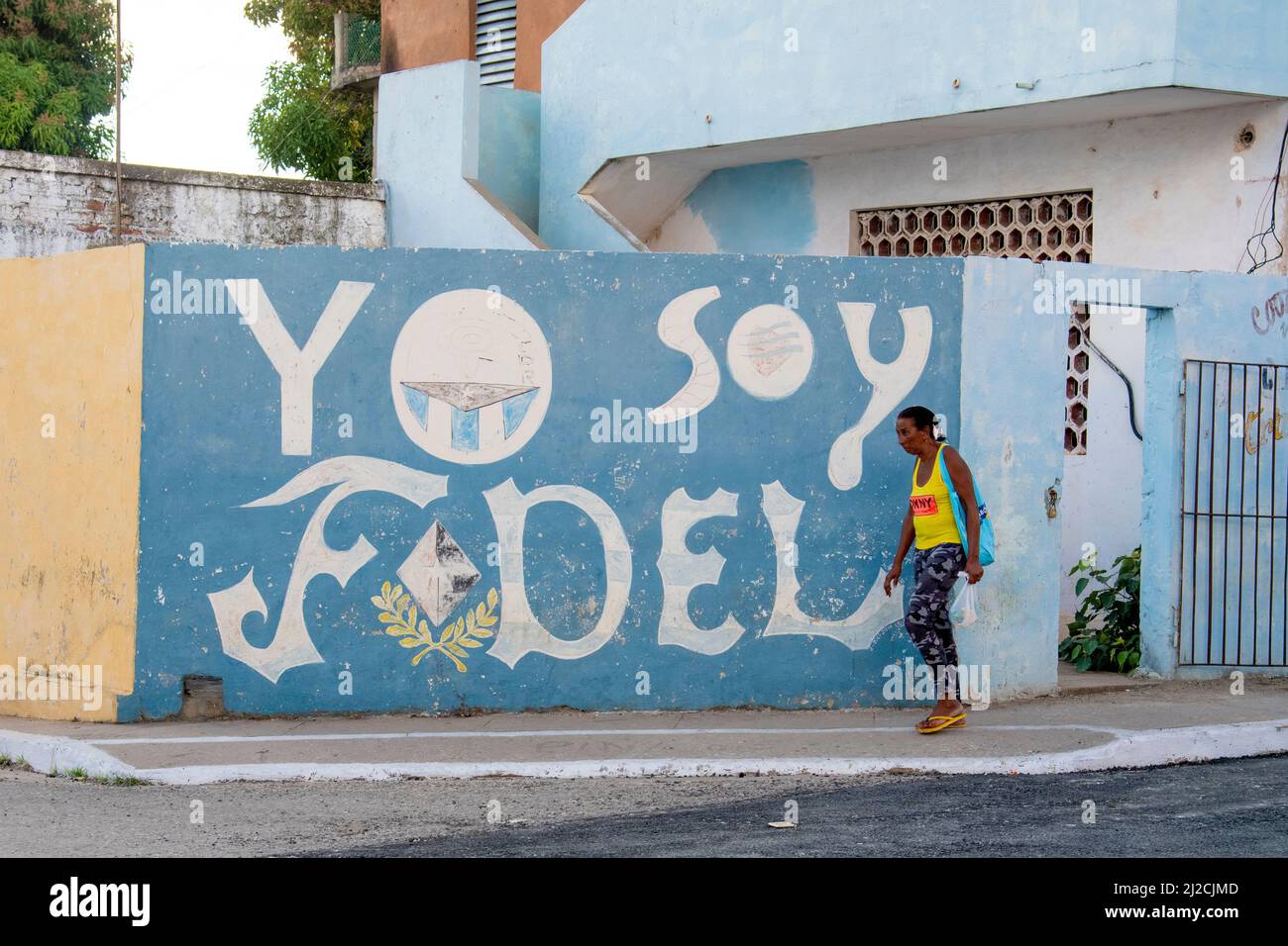 Donna che indossa un paio di infradito cammina accanto a un Yo Soy Fidel, io sono folle (Castro) murale tributo a Trinidad, Cuba. Foto Stock