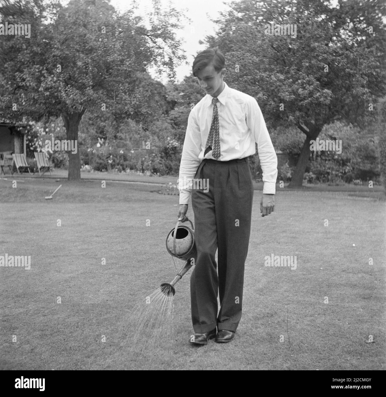 Figlio della famiglia Martineau nel giardino dell'Old Lodge a Terlow (Buckinghamshire) innaffiare il prato ca: Luglio 1954 Foto Stock