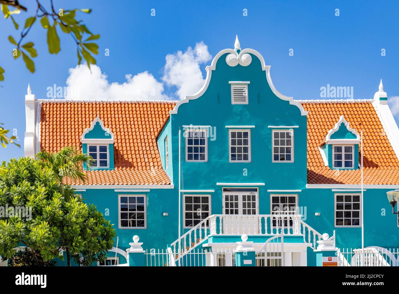 Bell'edificio con una facciata turchese, dettagli bianchi e un tetto arancione a Willemstad, Curacao Foto Stock