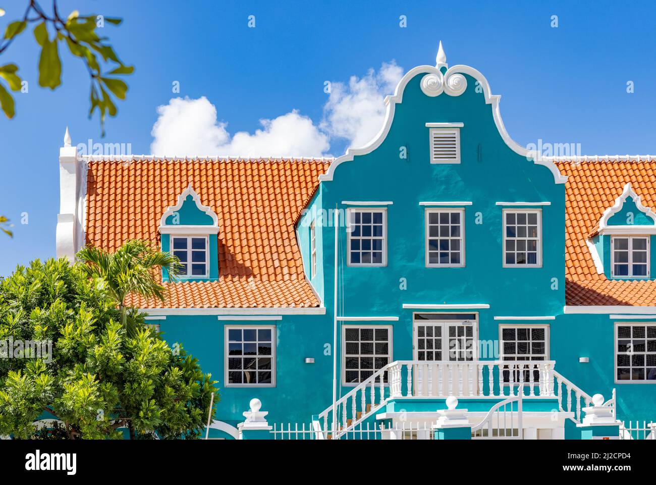 Bell'edificio con una facciata turchese, dettagli bianchi e un tetto arancione a Willemstad, Curacao Foto Stock