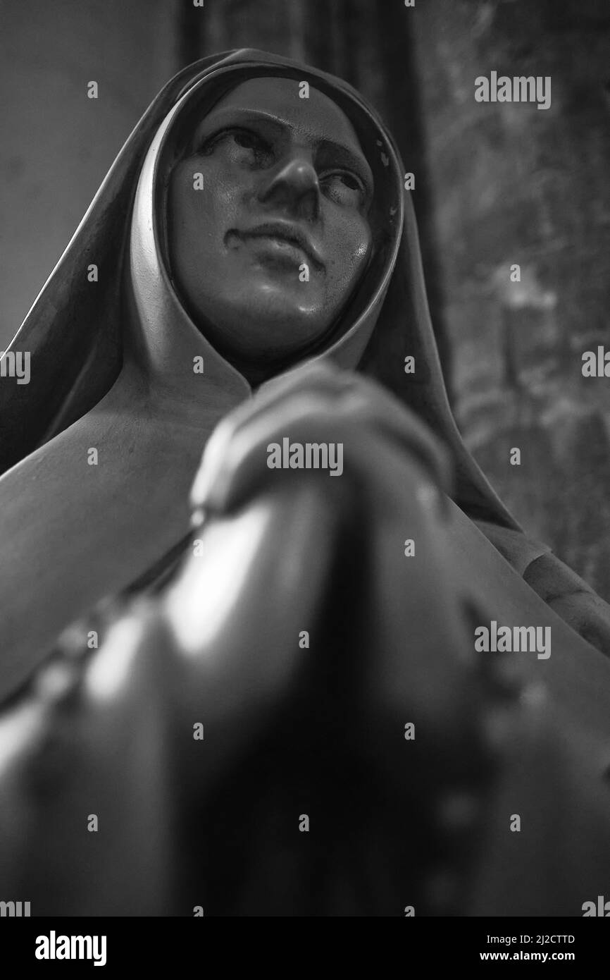 Nero e bianco basso angolo scatto della statua di una suora che prega nella Cattedrale di Saint Andre, Bordeaux, Francia Foto Stock