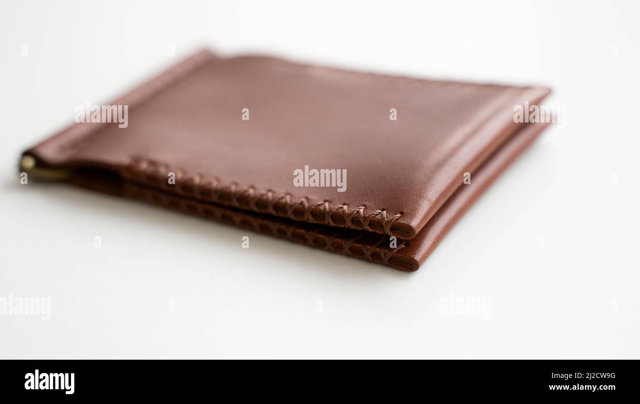 Il portafoglio in pelle fatto a mano con clip denaro da uomo vuoto e due  tasche per le carte si trova su un tavolo bianco. Messa a fuoco selettiva,  spazio di copia,