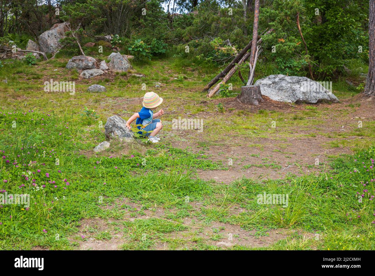 Bella vista del bambino carino che si riposa sulla pietra nel parco. Svezia. Foto Stock