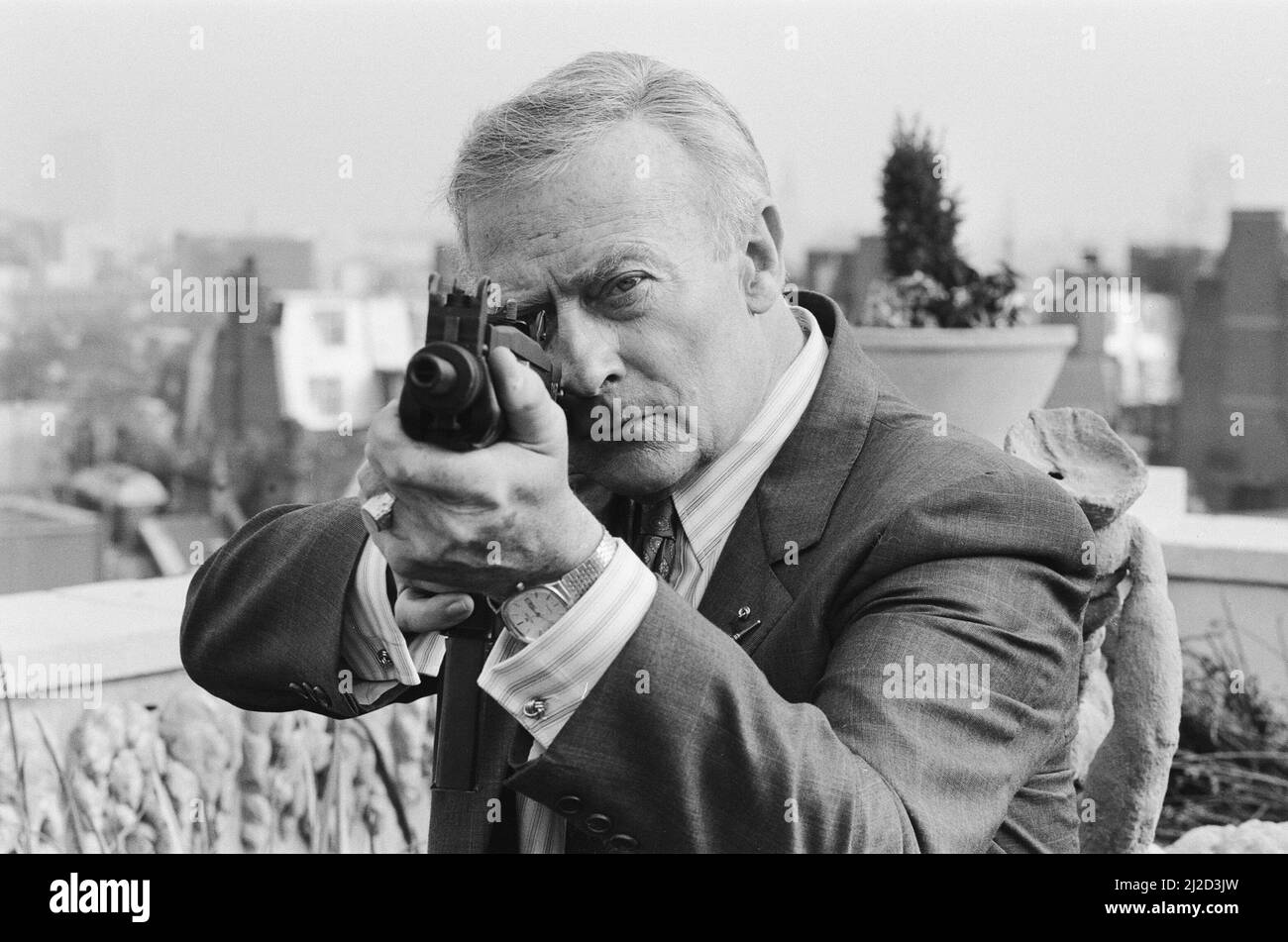 L'attore britannico Edward Woodward, che suona l'ex agente Robert McCall nella serie televisiva americana The Equalizer, posando a Londra con una mitragliatrice per promuovere la serie. 25th ottobre 1986. Local Caption l'equalizzatore Foto Stock