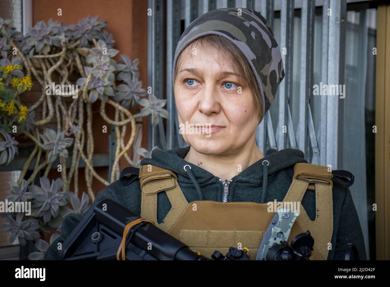 Vera donna civile Ucraina che tiene un fucile per difendere l'Ucraina. Cittadina femminile con guerra e arma a difesa della sua casa e della città. Foto Stock