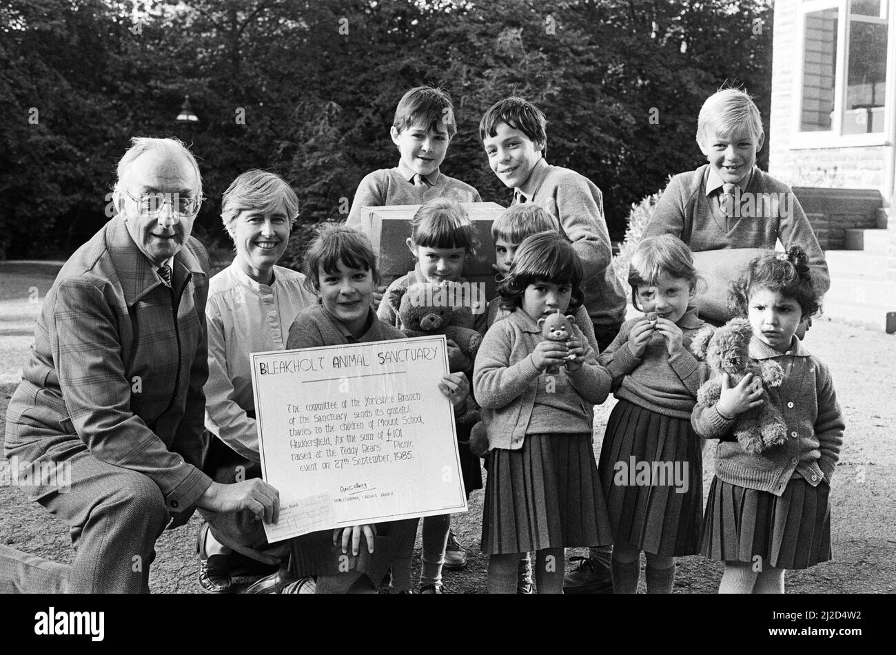 La ragazza capo Zoe Leeper presenta un assegno del £101 della Mount School di Edgerton al sig. Austin Clegg, presidente onorario del ramo dello Yorkshire del Bleakholt Animal Sanctuary a Ramslowl, Lancashire. Il denaro è stato raccolto da un picnic di orsacchiotto. Nella foto sono raffigurati anche l'insegnante di bambini Mrs Yvonne Wheelhouse, che ha organizzato l'evento, prefetti e altri allievi. 11th ottobre 1985. Foto Stock