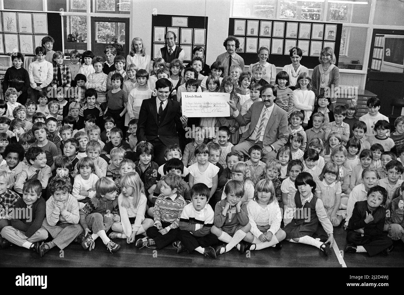 Un assegno per il £144 è presentato al sig. Michael Tottle (a sinistra) rappresentante dell'area del Royal National Institute for the Blind dal direttore della Linthwaite County Primary School, sig. Stretton Hobson. Circa 195 alunni hanno raccolto il denaro raccogliendo donazioni per le cartoline RNLI. 3rd ottobre 1985. Foto Stock